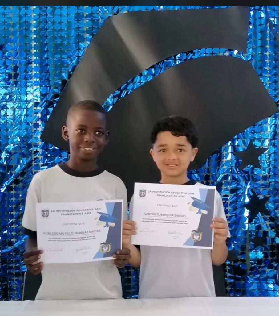 Two students holding school certificates
