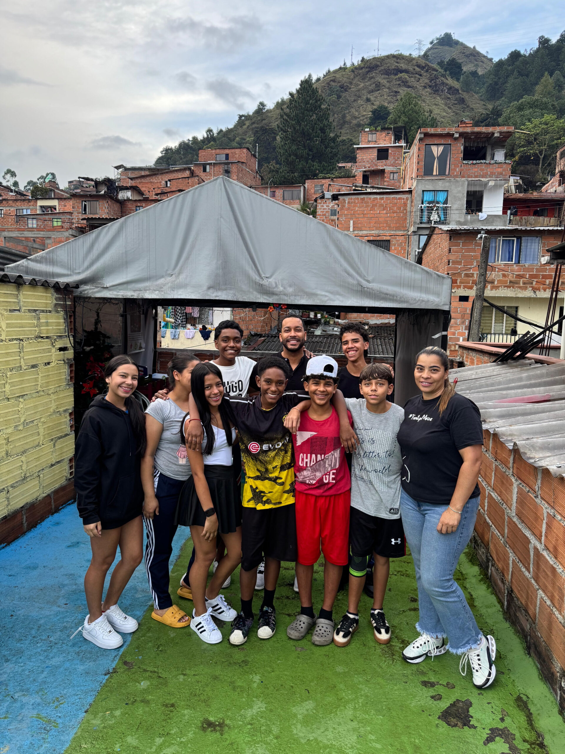 Group of youth and adults posing together on a rooftop patio in a hillside brick neighborhood