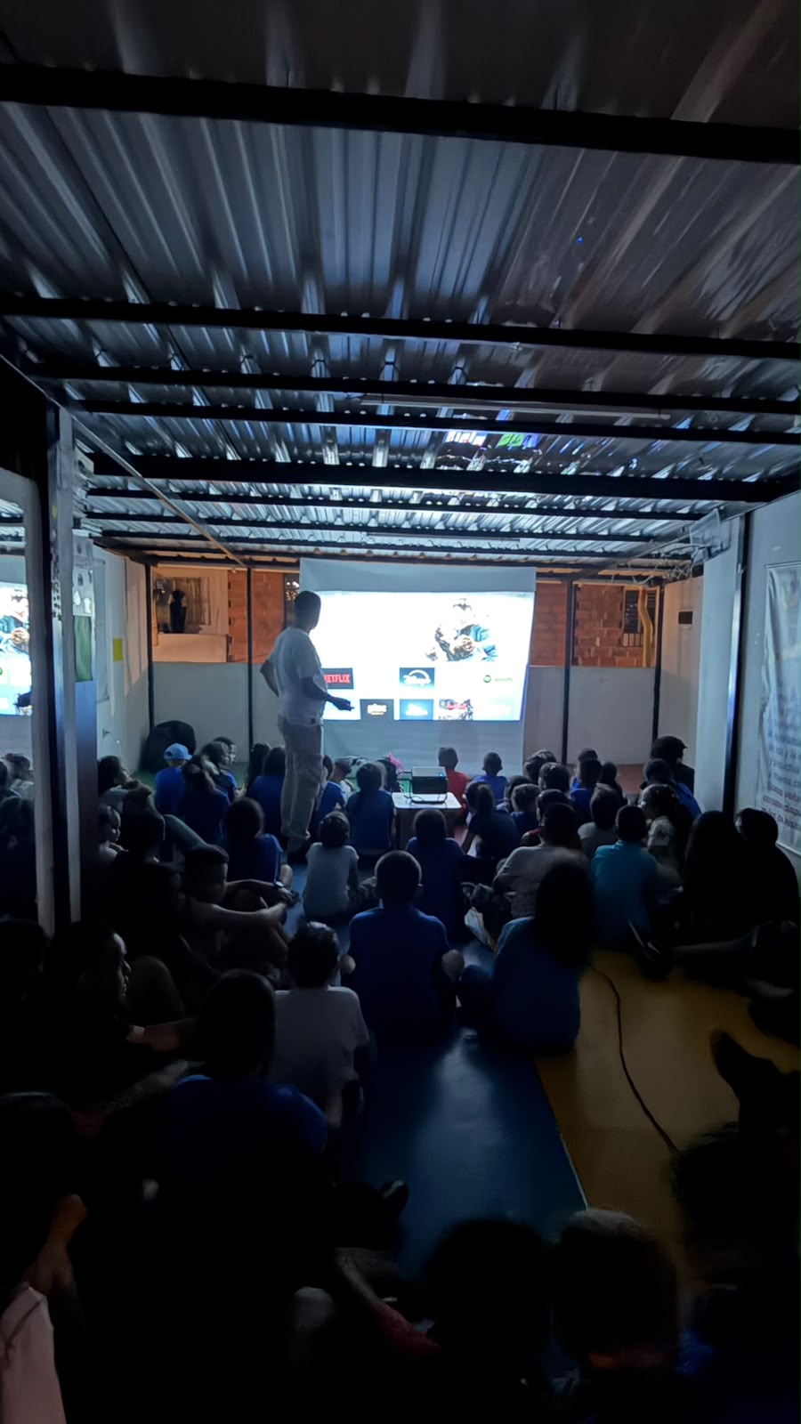 Large group of children watching a projected movie at night