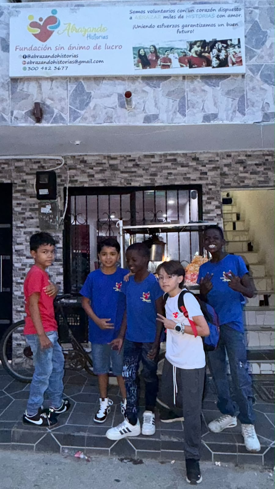 Boys posing outside a building with an Abrazando Historias foundation sign