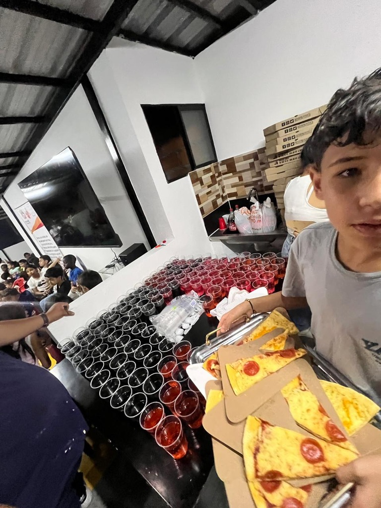 A boy next to the stack of pizza boxes.