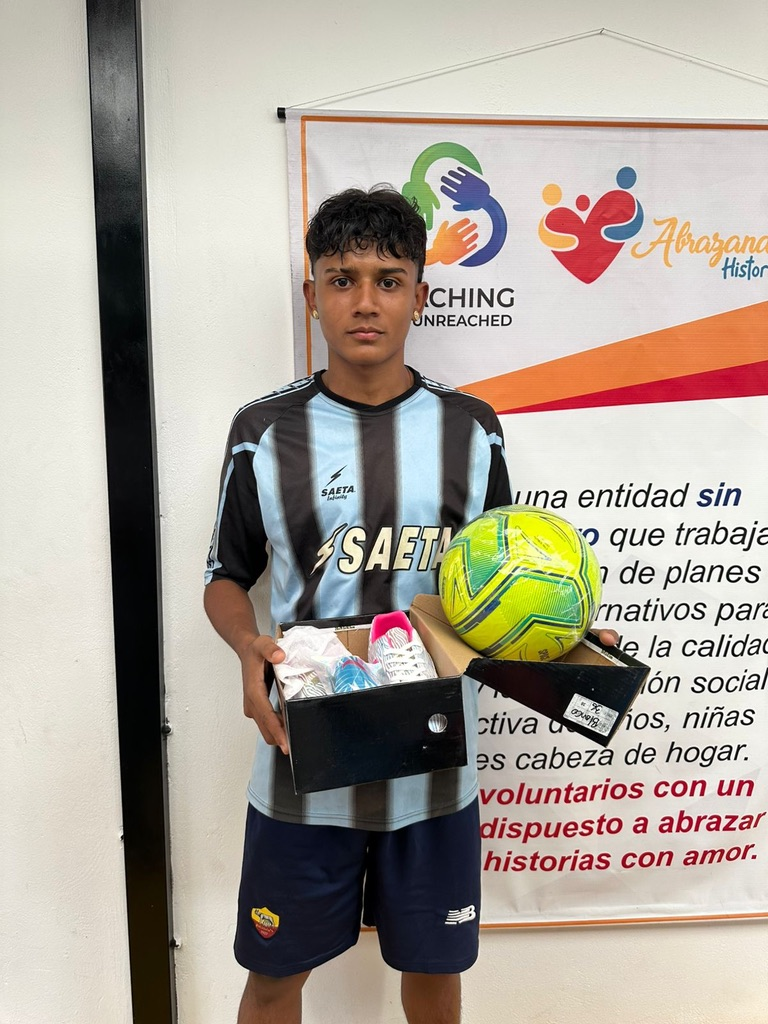 A young player with his new jersey, ball and cleats.