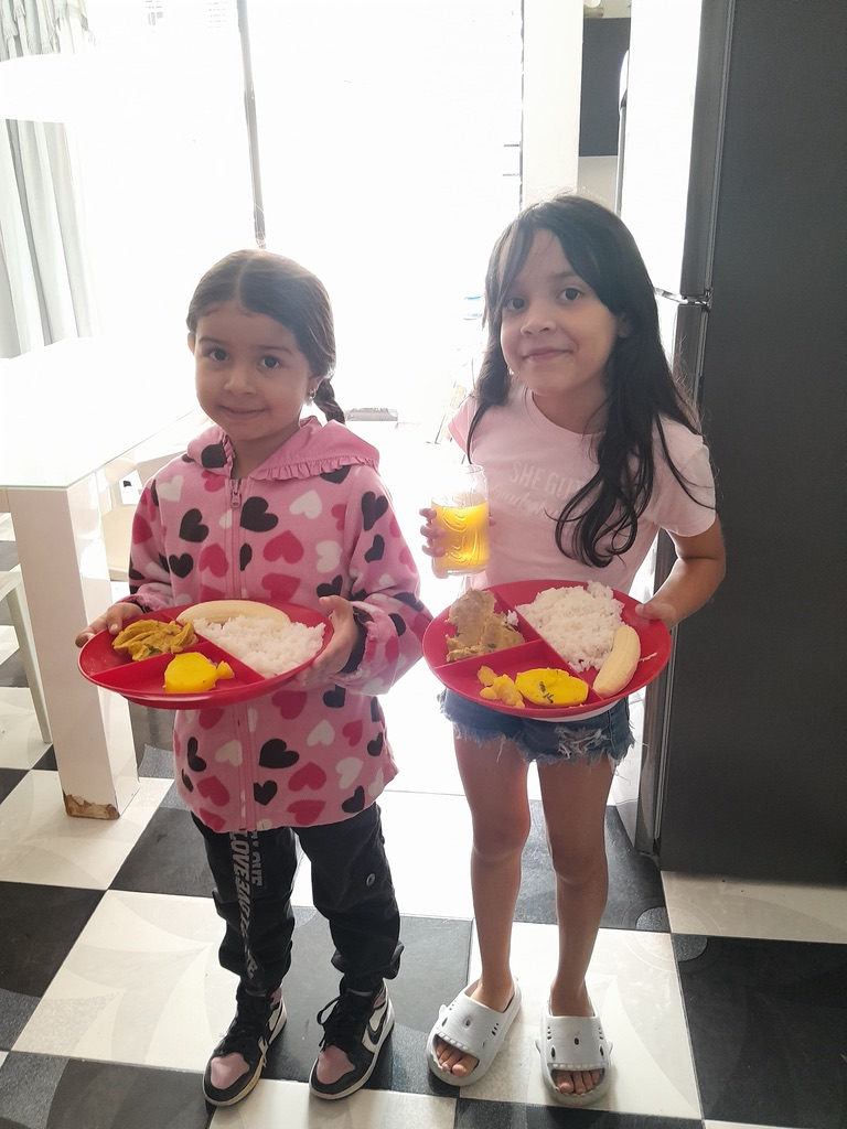 Two girls with their plates at a shared meal.