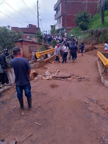 Families walk the muddy road after the landslide.