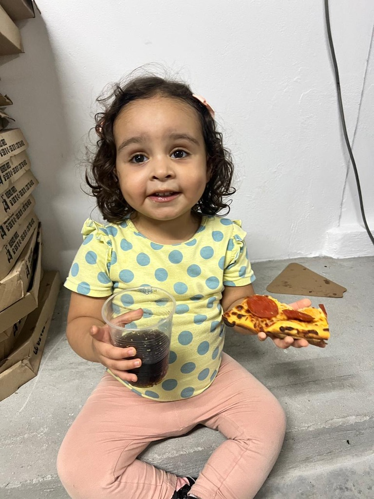 A toddler enjoys a slice of pizza.
