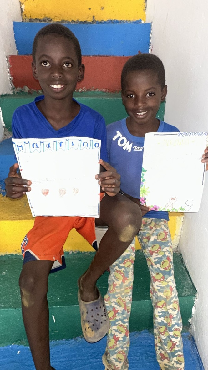 Two boys proudly show their certificates.