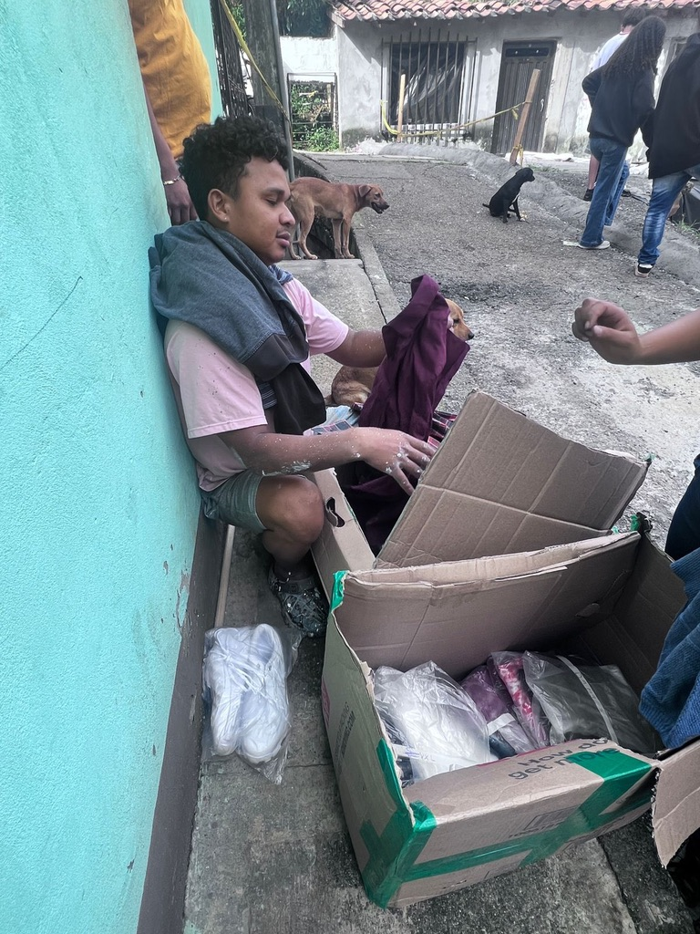 A young man looks through a box of donated clothes.